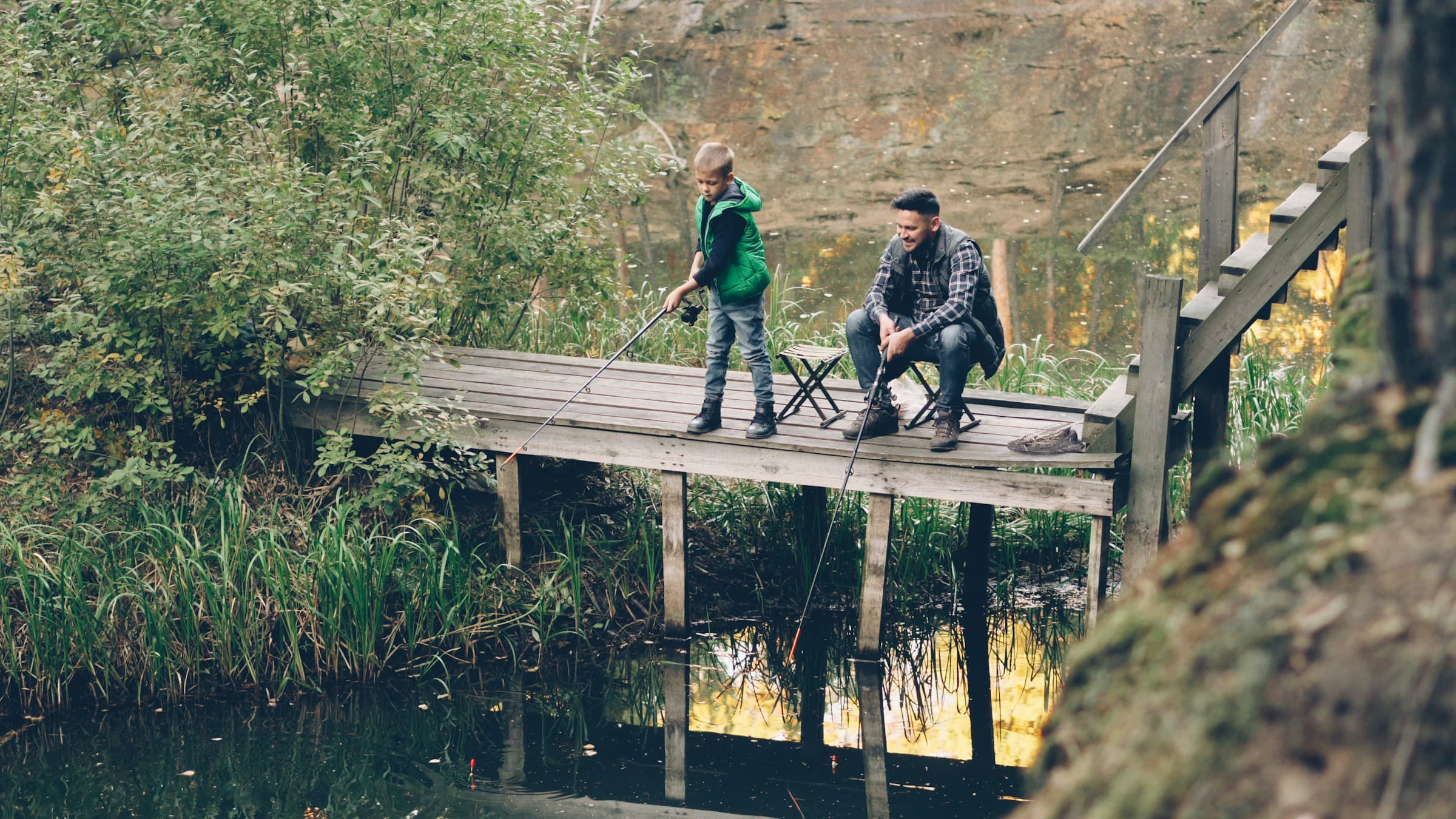 Father and son fishing together from a wooden dock